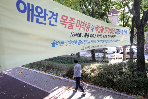 한 공원에 반려견의 목줄 미착용 및 배설물 방치 행위를 단속하는 내용의 현수막이 걸려 있다.(사진=뉴스1)