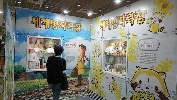 한 여성이 추억의 캐릭터를 선보인 세계명작부스 빨간머리앤의 캐릭터에 집중하는 모습
