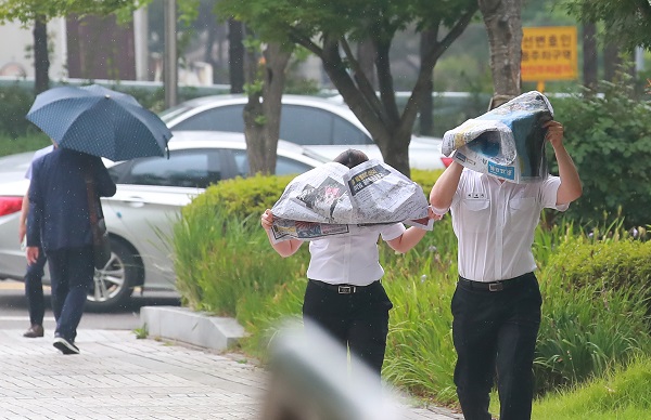 서울 지역에 비가 내리기 시작한 17일 오후 서울 서초구 서울고등법원 앞에서 법원 관계자들이 신문으로 머리를 가린 채 이동하고 있다.(사진=저작권자(c) 연합뉴스, 무단 전재-재배포 금지)