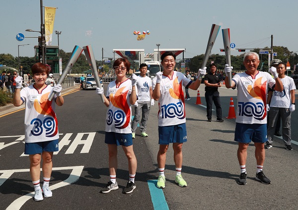 29일 오후 제100회 전국체육대회와 장애인전국체전 성화봉송 주자인 서울 아시안게임 3관왕 임춘애(왼쪽 두번째부터)와 사격 진종오가 서울 송파구 올림픽공원 앞에서 성화봉송을 마치고 다음주자인 여자핸드볼 은메달리스트 임오경(왼쪽), 주원홍 아시아테니스연맹 부회장에게 성화를 옮기고 있다.(사진=저작권자(c) 연합뉴스, 무단 전재-재배포 금지)