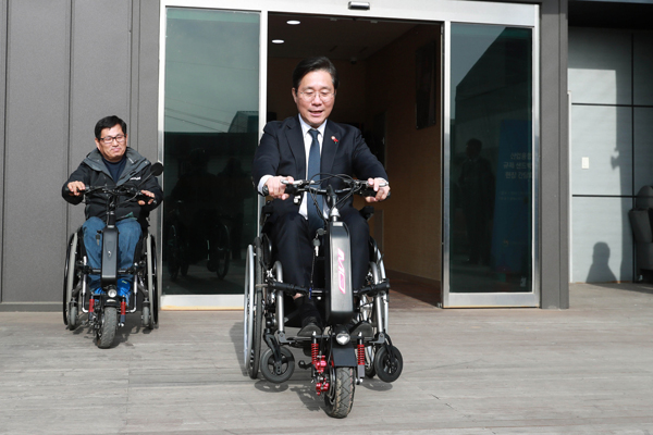 성윤모 (가운데) 산업통상자원부 장관이 지난달 경기 김포 ㈜알에스케어서비스를 방문, 수동휠체어인 전동보조키트를 탑승하고 있다. <사진=산업통상자원부 제공>