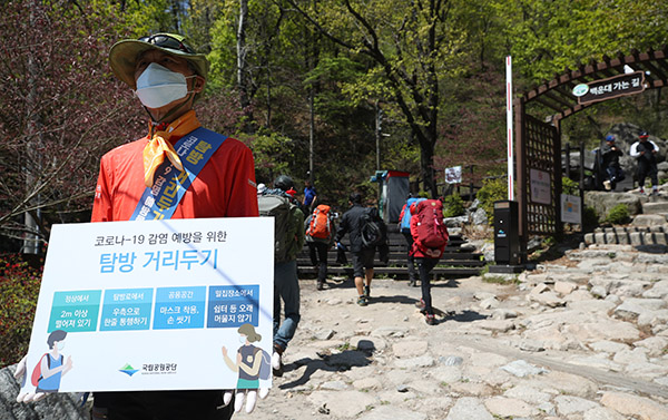 정부가 고강도 사회적 거리두기 강도를 다소 낮추기로 한 후 첫 주말인 26일 북한산 백운대탐방지원센터 앞에서 국립공원 국민구조단원이 코로나19 예방을 위한 탐방 거리두기 관련 안내를 하고 있다.(사진=저작권자(c) 연합뉴스, 무단 전재-재배포 금지)