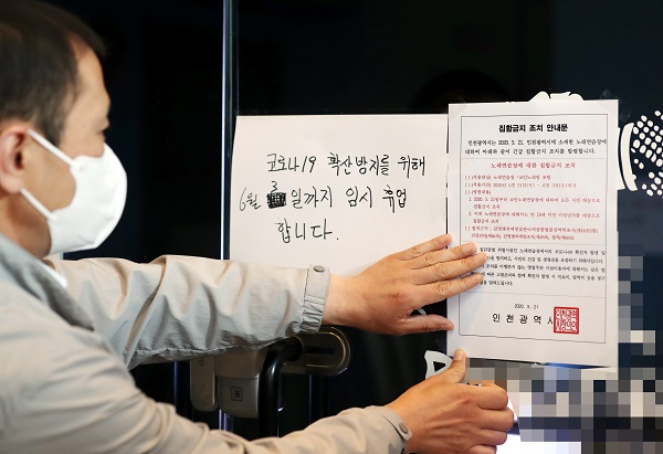 정부가 신종 코로나바이러스 감염증(코로나19) 확산을 우려해 인천지역 코인노래방에 집합금지 명령을 내린 21일 오후 인천시 연수구 한 코인노래방에서 연수구청 관계자가 집합금지 조치 안내문을 부착하고 있다. (저작권자(c) 연합뉴스, 무단 전재-재배포 금지)