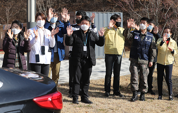 지난 3월 12일 경북 문경시 문경읍 서울대학교병원 인재원에 마련된 대구·경북 제3생활치료센터에서 첫 번째 격리해제자가 차를 타고 치료센터를 떠나자 센터의 의료진과 관계자들이 손을 흔들며 작별 인사를 하고 있다. (사진=저작권자(c) 연합뉴스, 무단 전재-재배포 금지)