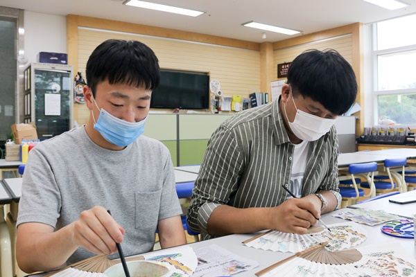 밑그림이 그려진 부채에 색을 칠해보는 민화 체험