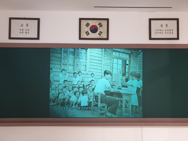 한국전쟁 후 폐허 속에서도 교육에 전념하는 오래된 흑백 다큐멘터리가 상영되고 있다.