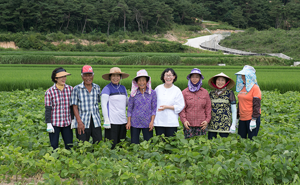 서현정 콩사랑 대표(오른쪽 네번째)가 싸리재마을 어르신과 함께 밭에서 밝게 웃고 있다. (사진=농업회사법인 콩사랑 제공)