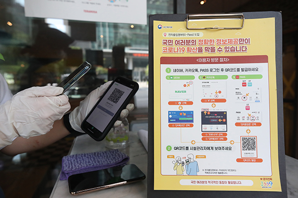서울의 한 카페에서 직원이 전자출입명부 기록을 위해 출입 손님들의 QR코드를 인식하고 있다. (사진=저작권자(c) 연합뉴스, 무단 전재-재배포 금지)