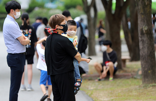 한 초등학교 앞에서 아이가 엄마품에 안겨있다. (사진=저작권자(c) 연합뉴스, 무단 전재-재배포 금지)