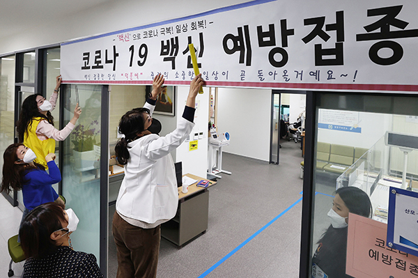 24일 서울 중랑구보건소에서 보건소 관계자들과 구청 직원들이 코로나19 예방접종 안내 현수막을 설치하고 있다.