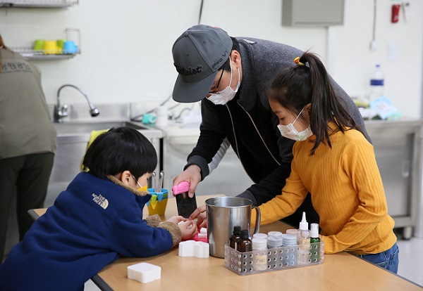 한 가족이 재활용 체험 프로그램에 참가해 만들기를 하고 있다.