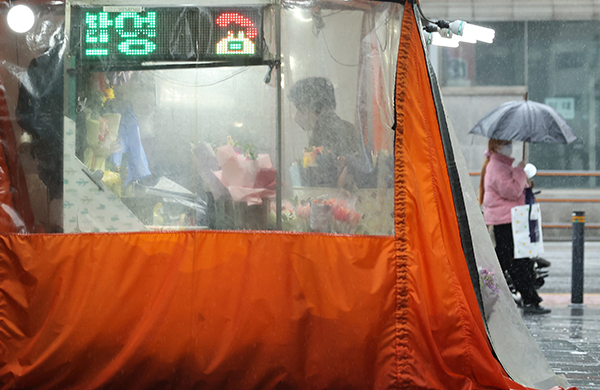 서울 종로구 관철동 젊음의 거리에서 꽃집을 운영하는 한 노점상이 비가 오는 가운데 영업을 준비하고 있다.