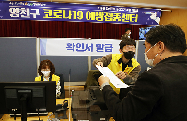 지난 15일 서울 양천구 목동 신종 코로나19 예방접종센터에서 시민들이 백신 접종 후 종이 확인서를 받고 있다.