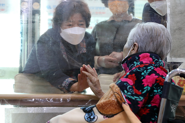 광주 동구 강남요양병원에서 90대 입원 환자와 딸이 비대면 면회를 하던 중 투명 가림막을 사이에 두고 손을 마주대고 있다.