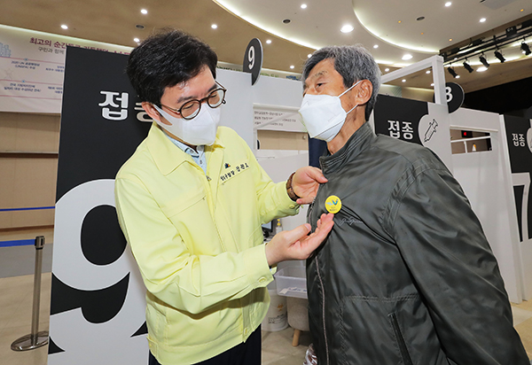 정원오 성동구청장이 지난 22일 오전 서울 성동구청에 설치된 서울시 1호 코로나19 예방 접종 센터에서 2차 접종을 마친 한 어르신에게 안심배지를 달아드리고 있다.