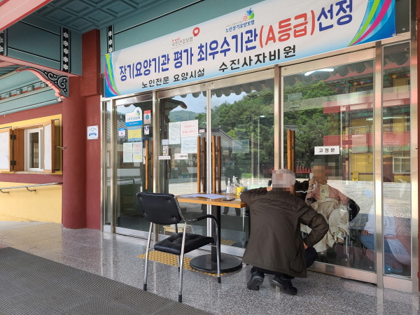 요양원에서 92세 노모와 유리창을 사이에 두고 전화로 면회를 하고 있다.