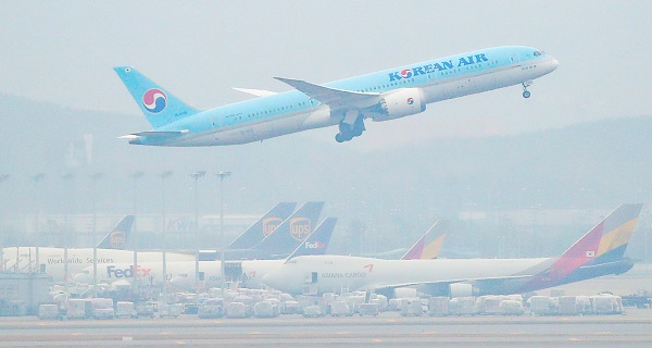 인천국제공항 주기장에 세워진 아시아나항공 여객기 위로 대한항공 여객기가 이륙하고 있다.(사진=저작권자(c) 연합뉴스, 무단 전재-재배포 금지)