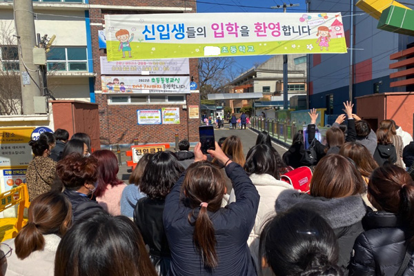지난 3월 2일, 입학식이 열린 아이의 교문 앞에서 학부모들이 손을 흔들고 있다.