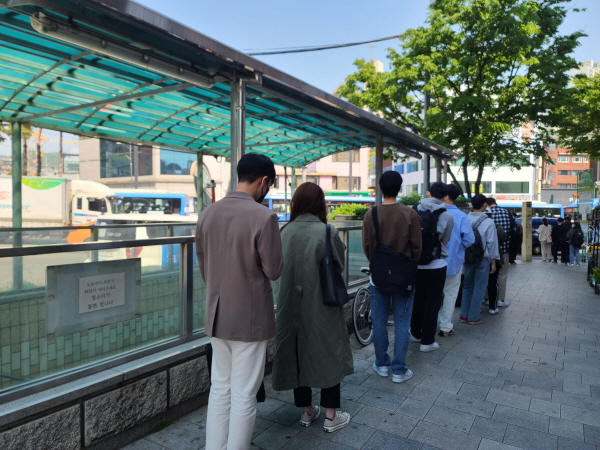 실외지만 학교 버스로 갈아타기 위해 대기하고 있는 학생들이 모두 마스크를 착용하고 있다.