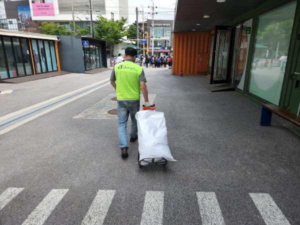 어르신이 손수레로 커피 찌꺼기를 옮기고 있다.