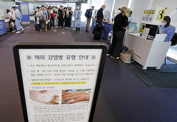 인천국제공항 제1터미널 입국장에 해외입국자들이 검역을 받기 위해 대기하고 있다. 승객들 앞에는 원숭이두창 관련 안내문이 세워져 있다. (사진=저작권자(c) 연합뉴스, 무단 전재-재배포 금지)