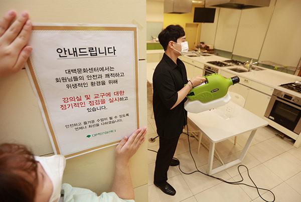 지난 19일 대구 중구 대구백화점 프라자점 문화센터에서 관계자들이 방역작업을 하며 방역 안내문을 붙이고 있다. (사진=저작권자(c) 연합뉴스, 무단 전재-재배포 금지)
