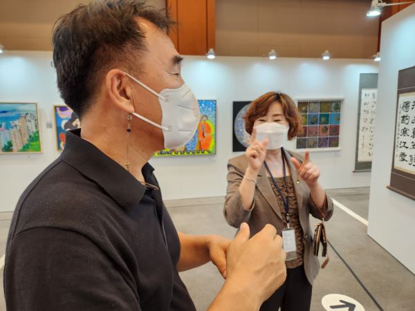 청각장애인 이성기 작가가 수어 통역 서비스를 받으면서 즉석 인터뷰에 응하고 있다.
