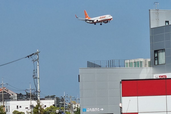 제주공항 인근 건물 위로 비행 중인 항공기 이미지