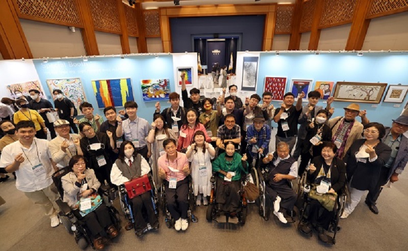 Participating artists, who have been active in their work despite developmental, physical, and hearing disabilities, are taking commemorative photos while drawing hand hearts in the special exhibition of disabled artists, 'Into the People, Into Harmony,' which opened on August 31 last year at the Cheongwadae Chunchugwan in Jongno-gu, Seoul.  (Photo = Ministry of Culture, Sports and Tourism)