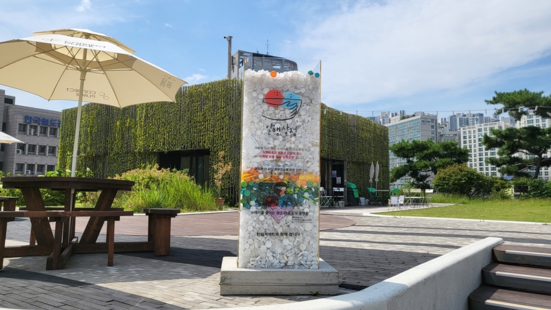 상점 입구에 병뚜껑을 활용해 만든 간판이 놓여 있다.