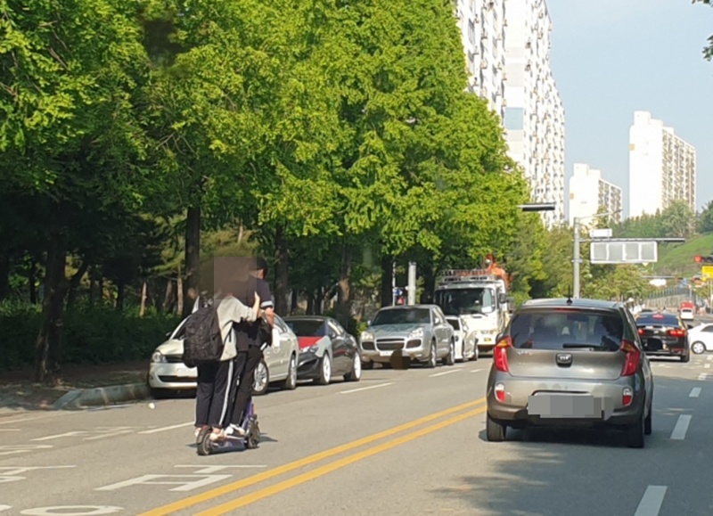 아무런 보호 장비 없이 전동킥보드를 타고 도로를 질주하는 학생들.