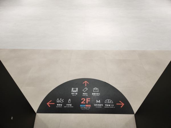 모두예술극장 2층 엘리베이터에서 내리니 바닥에 화살표 및 이미지가 포함된 길 안내도가 있다.