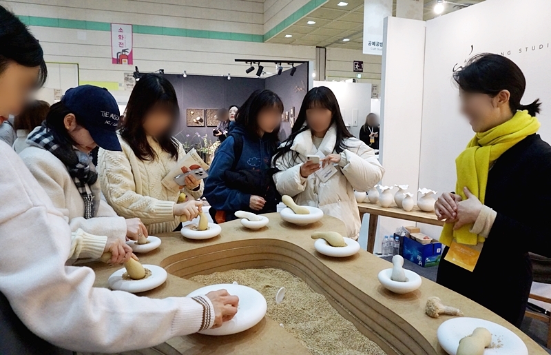 작가는 식기에 관해 많은 이와 소통하고 싶어했다. 작가의 작품으로 깨를 갈고 있는 사람들.