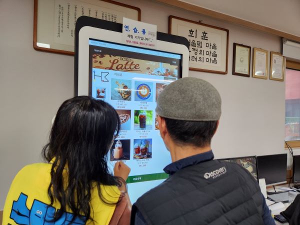 키오스크 사용을 어려워하는 어르신을 본 스마트경로당동행단이 천천히 설명해주고 있다.