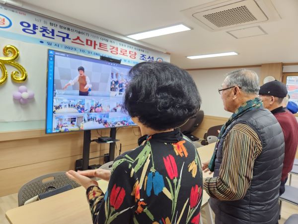 어르신들이 스마트TV에 나오는 웃음치료 강사의 말에 따라 박수를 치고 있다.