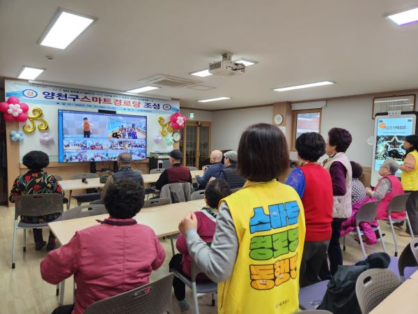 어르신들이 스마트TV에 나오는 웃음치료 강사의 노래와 춤을 따라서 즐기고 있다.