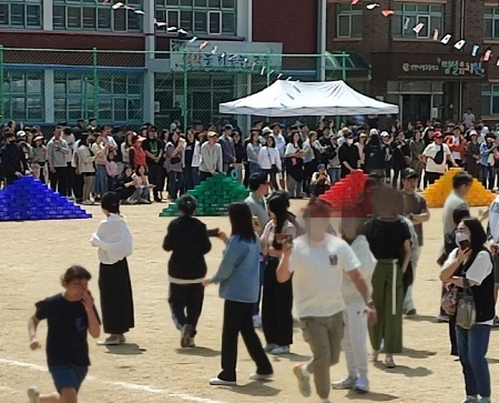 한 아빠가 아이와 함께 뛰며 휴대폰으로 동영상을 찍고 있다.