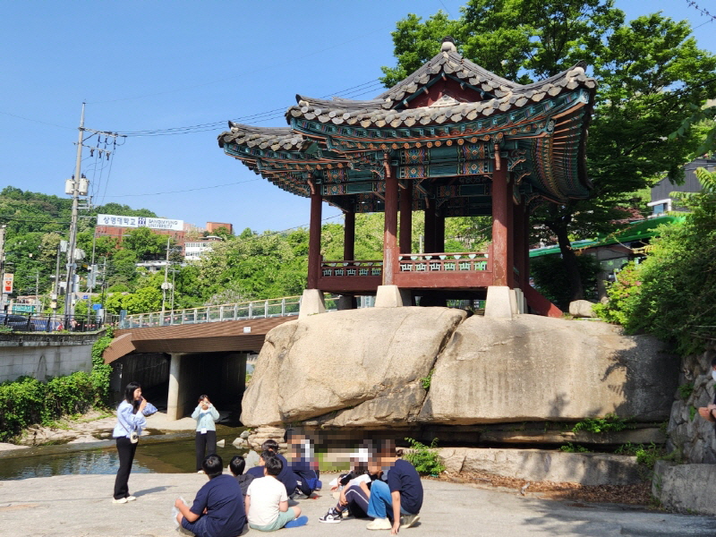 세검정에 집결한 학생들은 너른바위에 앉아서 세검정의 유래에 대한 이야기를 듣고 있다.