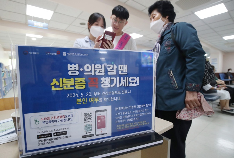 건강보험 본인확인 의무화 제도가 전국 병·의원과 요양기관 등에서 일제히 시행된 20일 대구 중구 계명대학교 대구동산병원에서 신분증을 지참하지 않은 80세 할머니가 자원봉사자의 도움을 받아 스마트폰에 모바일건강보험증 앱을 설치하고 있다.(ⓒ뉴스1, 무단 전재-재배포 금지)