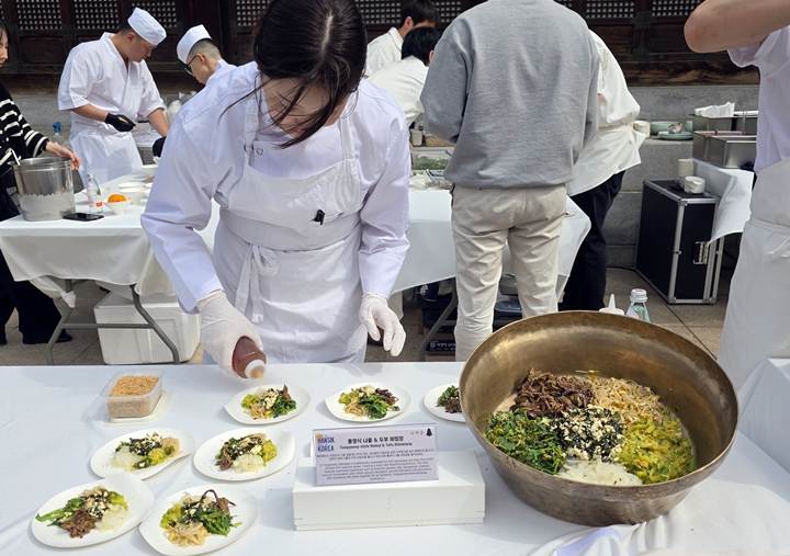 셰프가 나물을 담고 있다.