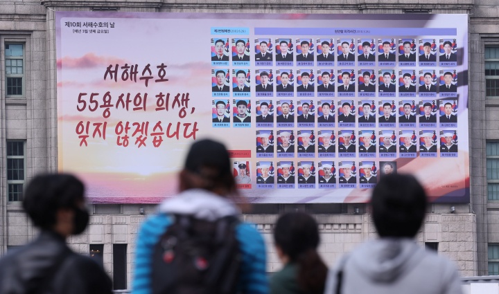 서해수호의 날을 하루 앞둔 27일 서울 중구 서울도서관 꿈새김판에 새겨진 55명 용사의 이름과 사진 앞으로 시민들이 이동하고 있다. (ⓒ뉴스1, 무단 전재-재배포 금지)