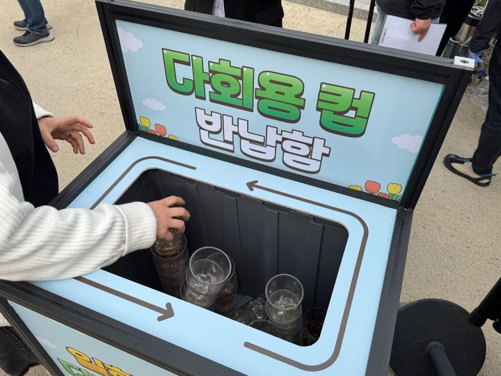 음료를 다 마신 방문객이 다회용 컵 반납함에 컵을 넣고 있는 모습.