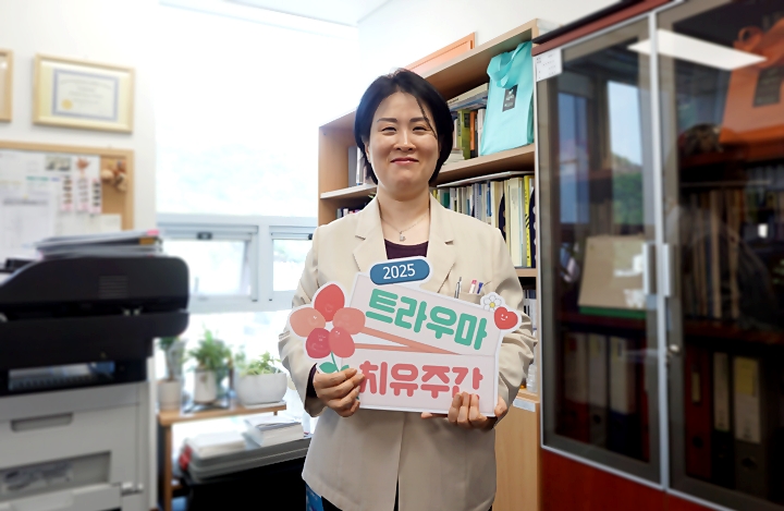 심 센터장이 '트라우마 치유주간' 홍보물을 보이고 있다.