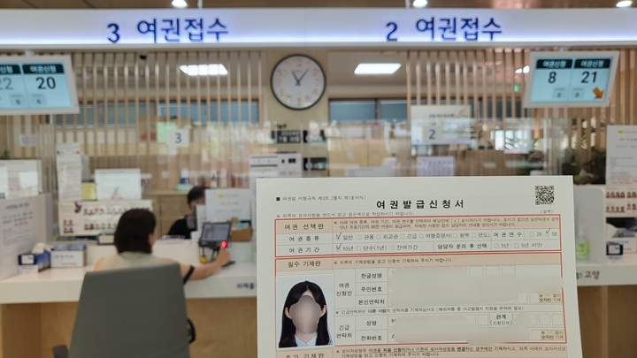 여권발급신청서를 들고 창구 앞에서 기다리고 있다.