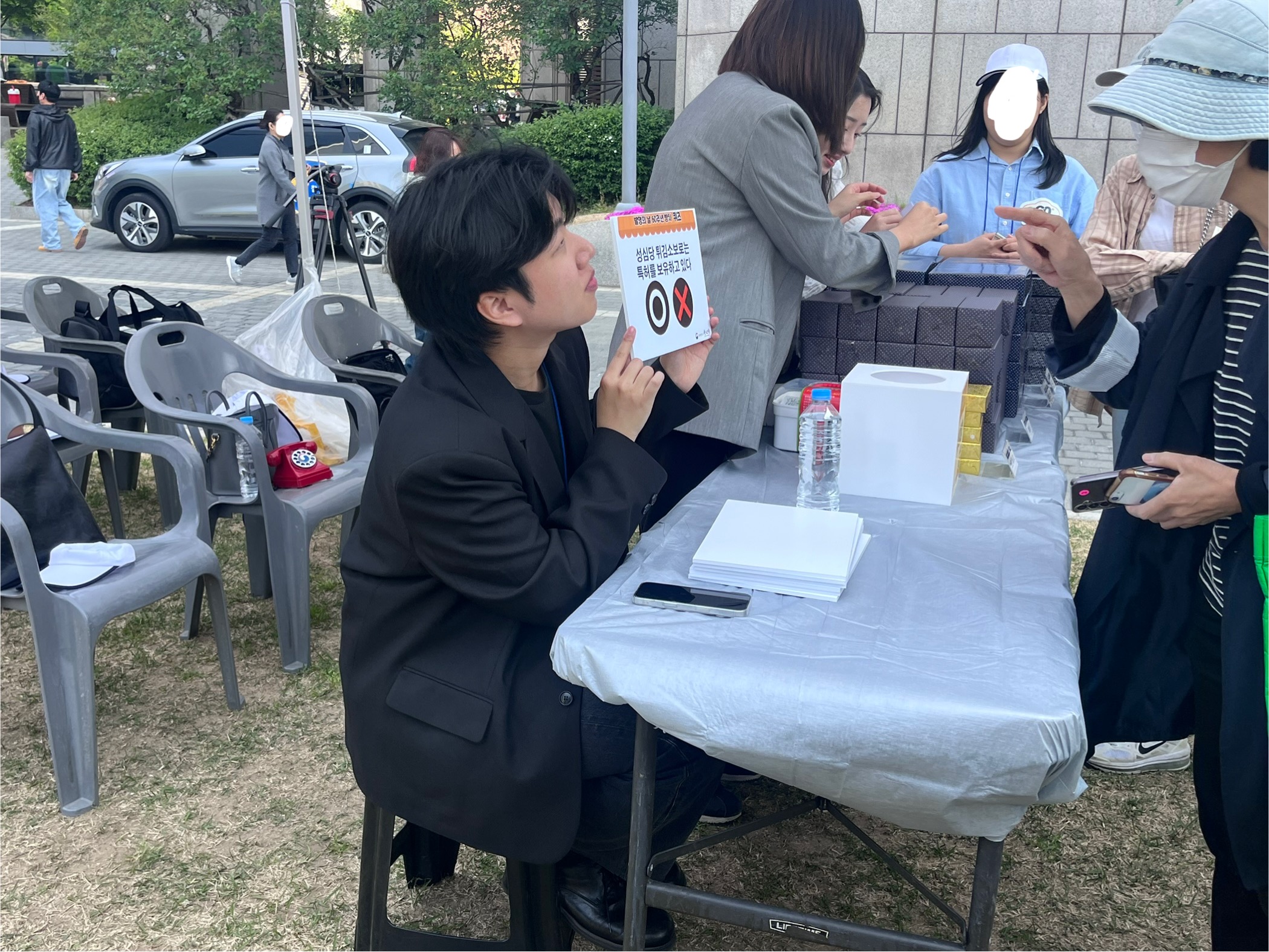 특허청 직원이 OX 퀴즈판을 들고 시민과 대화하며 퀴즈를 진행하는 모습.