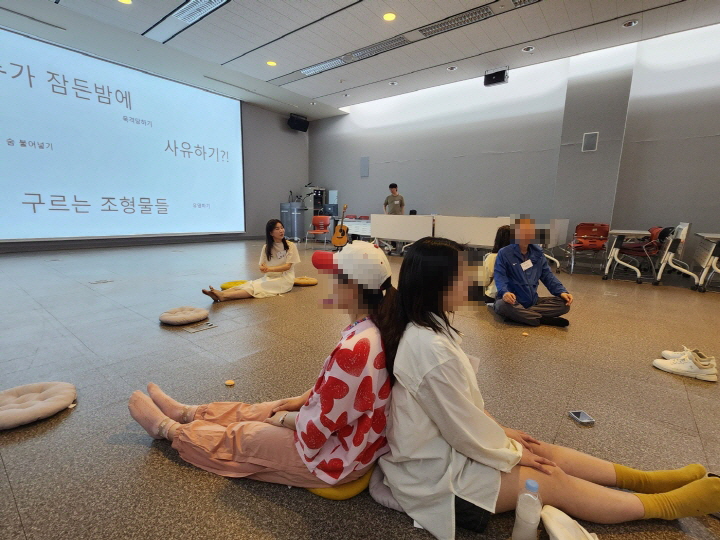 참여자가 두 명이 짝을 이뤄서 서로의 등을 댄 채로 반가사유상이 되어 보고 있다.