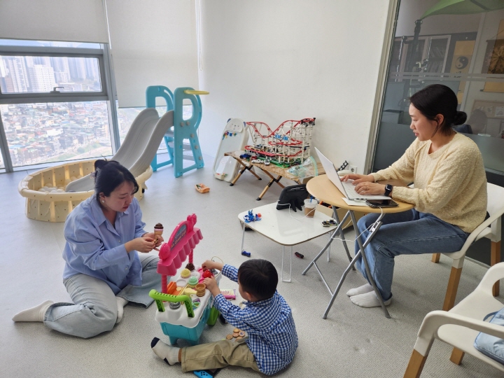 사내 키즈룸이 있어서 자녀와 함께 출근한 직원이 자녀를 돌보면서 일하고 있다.