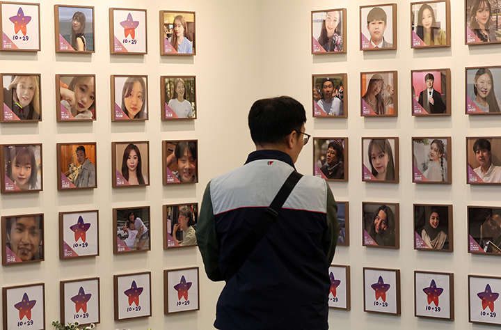 서울 종로구 적선현대빌딩에 열린 '10·29 이태원 참사 기억·소통공간 이전 별들의 집' 개소식에서 한 관계자가 희생자들의 사진을 바라보고 있다. 2024.11.10 (ⓒ뉴스1, 무단 전재-재배포 금지)