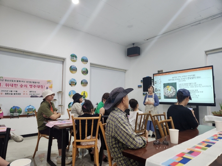 행주산성 정상에 있는 충의정에서 참여자들이 연잎밥 시식에 앞서 가와지쌀과 연잎밥에 대한 설명을 듣고 있다.