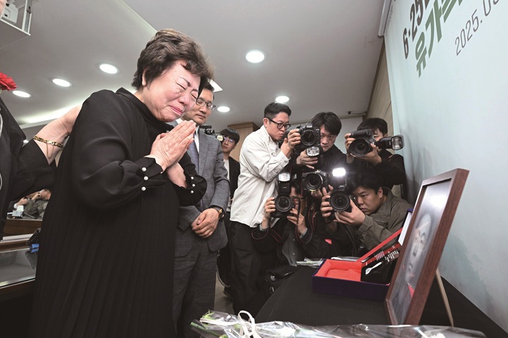 송재숙 씨가 아버지 송영환 일병의 영정 앞에 하얀색 카네이션을 바치고 손을 모으고 있다. 송 씨는 5년 전 유가족 유전자 시료 채취에 참여한 덕분에 아버지 얼굴을 마주할 수 있었다. 사진 국방부 유해발굴감식단